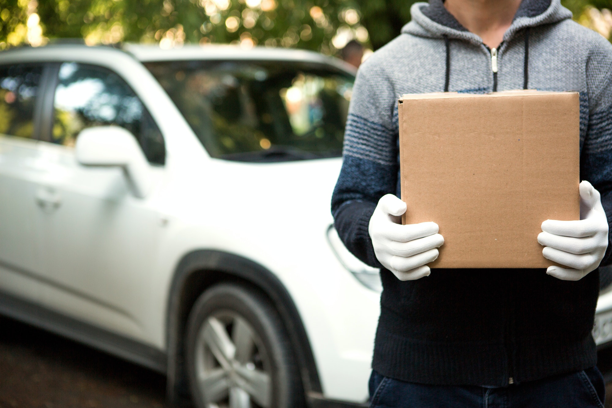 A cardboard box with space for text in the hands of a male courier in white gloves