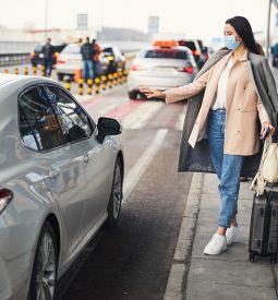 Stylish woman in medical mask taking cab at airport